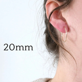 Gold hoop earring worn by a person with '20mm' text on a light background