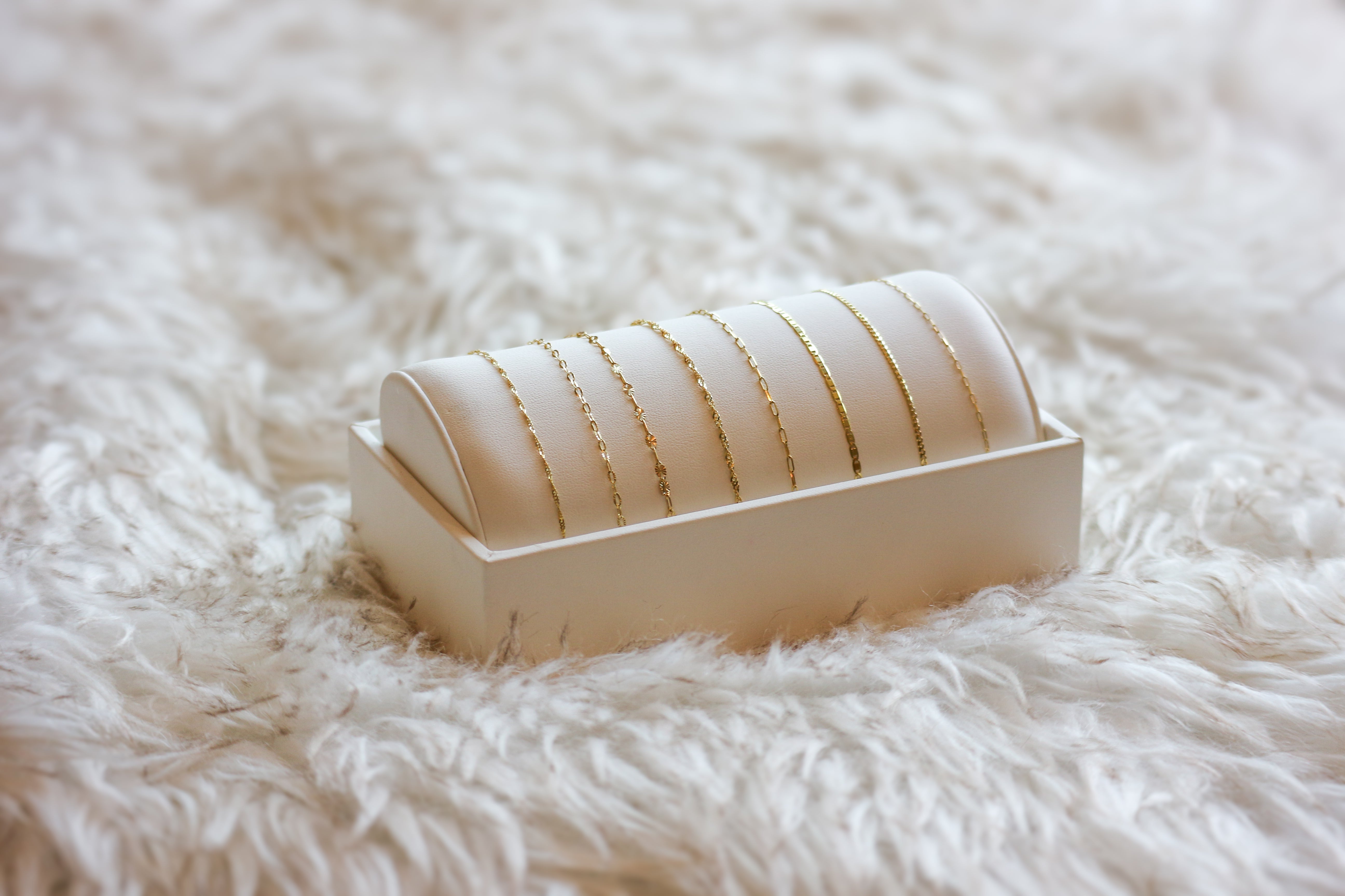 bracelet chains and permanent jewelry on white bracelet bar