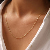 Gold necklace on a person wearing a white shirt