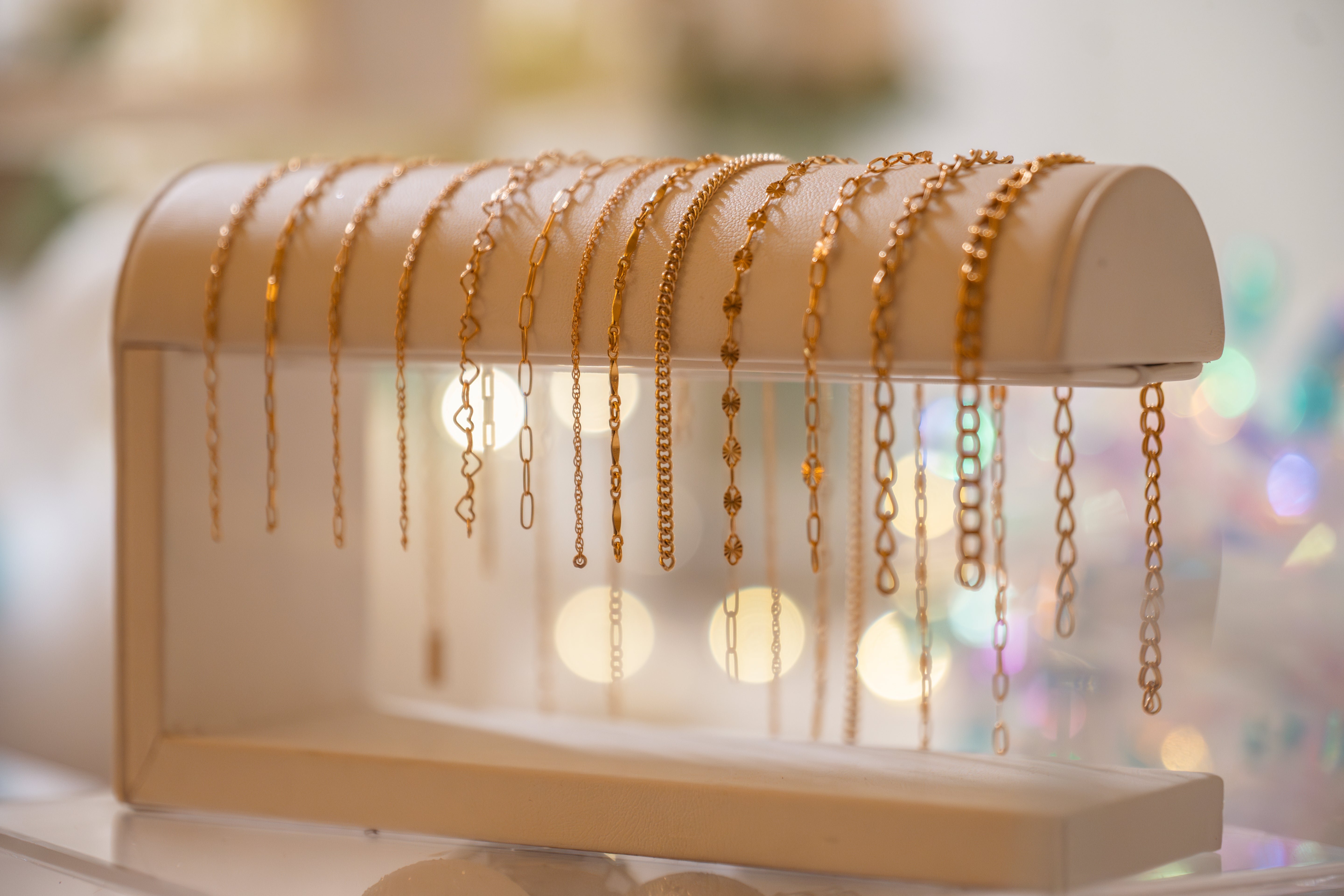 Bracelet chains for permanent jewelry on a white leather bar.