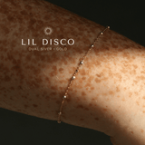 Gold bracelet on a wrist with 'LIL DISCO' branding.