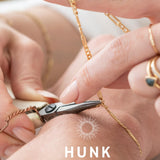 A close-up image of a bracelet with interlocked gold chains against a light background.